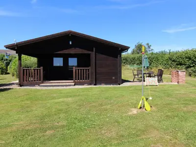 a small cabin with a sign in the grass at Maple Lodge in Bodmin
