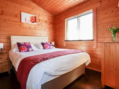 a bedroom with a bed in a wooden cabin at Cedar Lodge in Bodmin