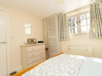 a bedroom with a bed and a dresser and a window at Atlantic View in Tintagel