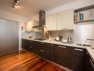 a kitchen with white cabinets and wooden floors at Rock Rose in Downderry
