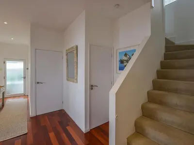 a staircase in a home with white walls and wood floors at Rock Rose in Downderry