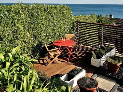 a wooden deck with a table and chairs and the ocean at Rock Rose in Downderry