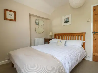 a bedroom with a large bed with white sheets at Primrose Cottage in Penryn