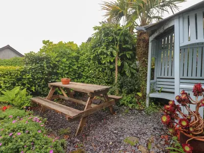 a wooden picnic table next to a blue building at 2 The Cottages in Ludgvan