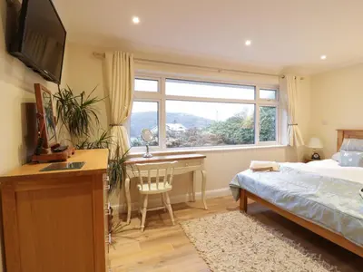 a bedroom with a bed and a desk and a window at Treetops in Fowey