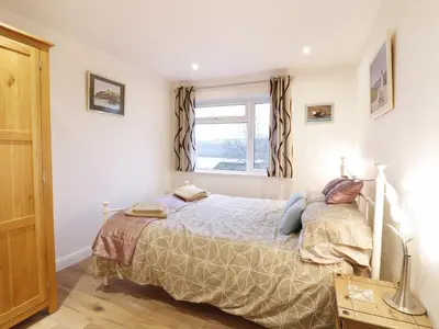 a bedroom with a bed and a window at Treetops in Fowey