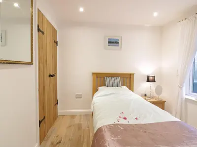 a small bedroom with a bed and a window at Treetops in Fowey