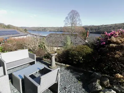 a patio with two chairs and a view of a lake at Treetops in Fowey