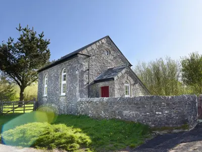 an old stone building with a red door at Moor View Chapel in Camelford