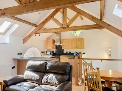 a living room with a leather couch and a kitchen at Moor View Chapel in Camelford
