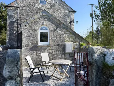 a table and chairs in front of a stone building at Moor View Chapel in Camelford
