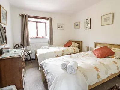 a bedroom with two beds and a desk at Brunnion Cottage in Hayle
