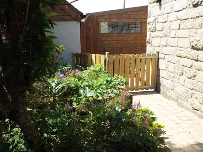 a garden with a wooden fence and some flowers at Brunnion Cottage in Hayle