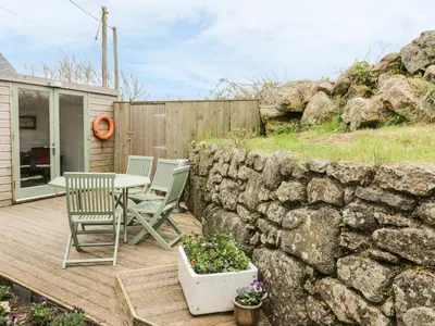 a patio with a table and chairs and a stone wall at Brunnion Cottage in Hayle