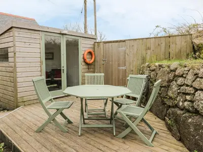 a table and four chairs on a wooden deck at Brunnion Cottage in Hayle