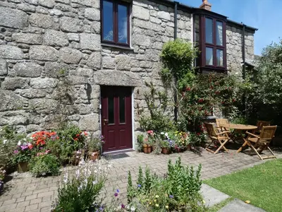 a stone house with a red door and some flowers at Brunnion House in Hayle