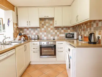 a kitchen with white cabinets and a sink at Brunnion House in Hayle