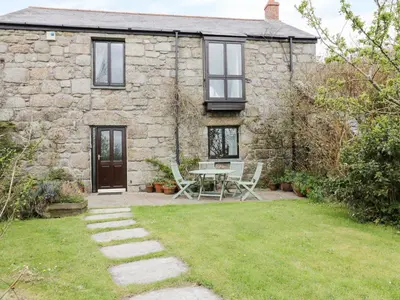 a stone cottage with a table and chairs in front of it at Brunnion House in Hayle