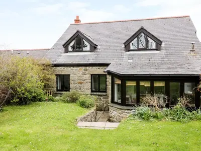 an old stone house with windows and a yard at Brunnion House in Hayle