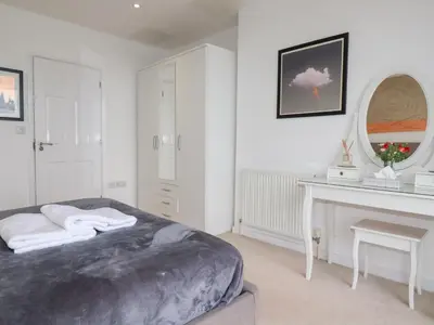 a white bedroom with a bed and a desk at Buena Vista in Newquay
