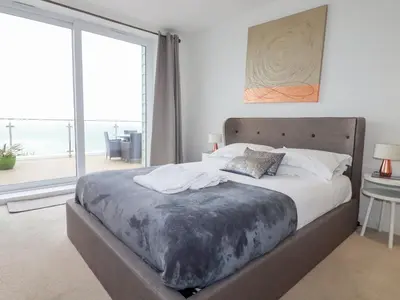 a large bed in a bedroom with a large window at Buena Vista in Newquay