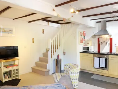 a kitchen and living room with a couch and a tv at Hele Stone Cottage in Launceston
