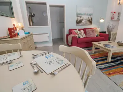 a living room with a table and a red couch at Beachcomber in Marazion