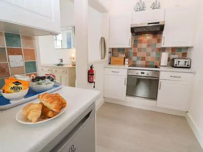 a kitchen with white cabinets and a plate of croissants at Beachcomber in Marazion