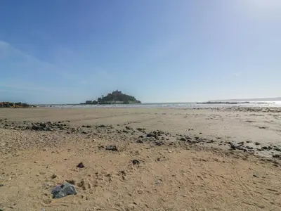 an empty beach with an island in the ocean at Beachcomber in Marazion