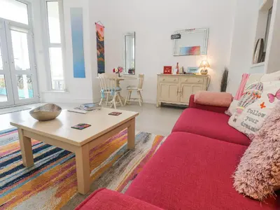 a living room with a red couch and a table at Beachcomber in Marazion