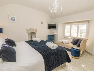 a bedroom with a large bed and a living room at Sea Cliff Cottage in Pentewan