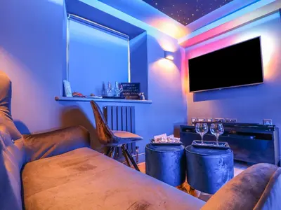 a room with two bar stools and a flat screen tv at Sea Cliff Cottage in Pentewan