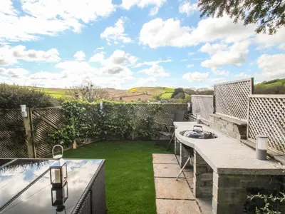 a patio with a table and a swimming pool at Sea Cliff Cottage in Pentewan