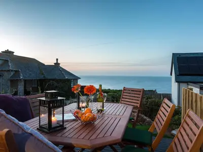 a wooden table with a bowl of fruit on a patio at Godrevy in St Ives