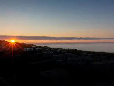 a sunset over a city with the sun setting over the ocean at Godrevy in St Ives