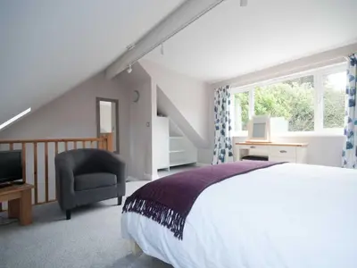 a bedroom with a bed and a chair and a window at The Beach House in Crantock