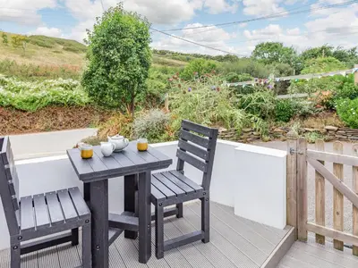 a wooden table and two chairs on a deck at The Beach House in Crantock
