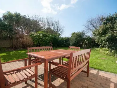 a wooden picnic table and two benches sitting on a brick patio at Bay View House in Crantock