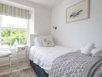 a white bedroom with a bed and a window at Dale Cottage in Crantock