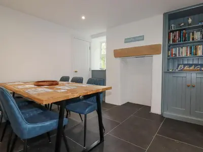 a dining room with a wooden table and blue chairs at Dale Cottage in Crantock