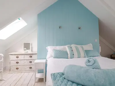 a bedroom with a bed with a blue wall at Dale Cottage in Crantock