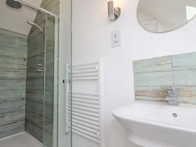 a bathroom with a shower and a sink and a mirror at Dale Cottage in Crantock