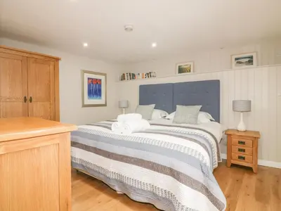 a bedroom with a large bed with a blue headboard at The Bolthole in Crantock