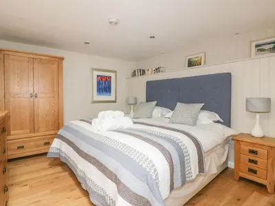 a bedroom with a large bed with a blue headboard at The Bolthole in Crantock