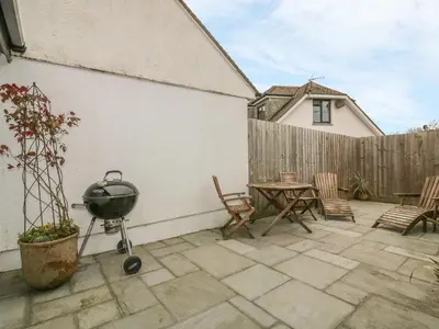 a patio with a grill and a table and chairs at The Bolthole in Crantock