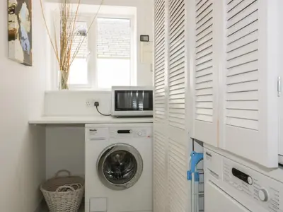 a white laundry room with a washing machine and a microwave at Offshore in Newquay
