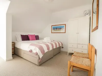 a bedroom with a bed with pink pillows and a chair at Offshore in Newquay