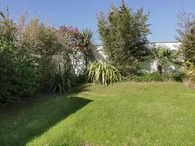 a yard with green grass and trees and a building at Offshore in Newquay