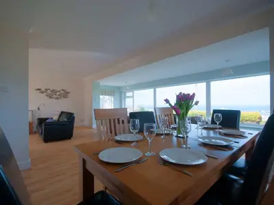 a dining room table with plates and wine glasses at Crantock Bay House in Crantock