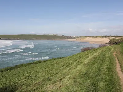 a grassy hill with a view of a beach at Crantock Bay House in Crantock